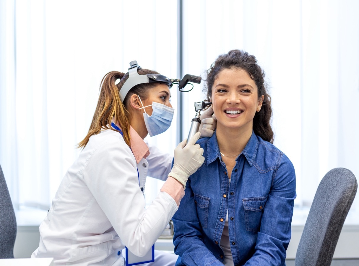 An audiologist examining a patient&rsquo;s ear with an otoscope during a hearing appointment